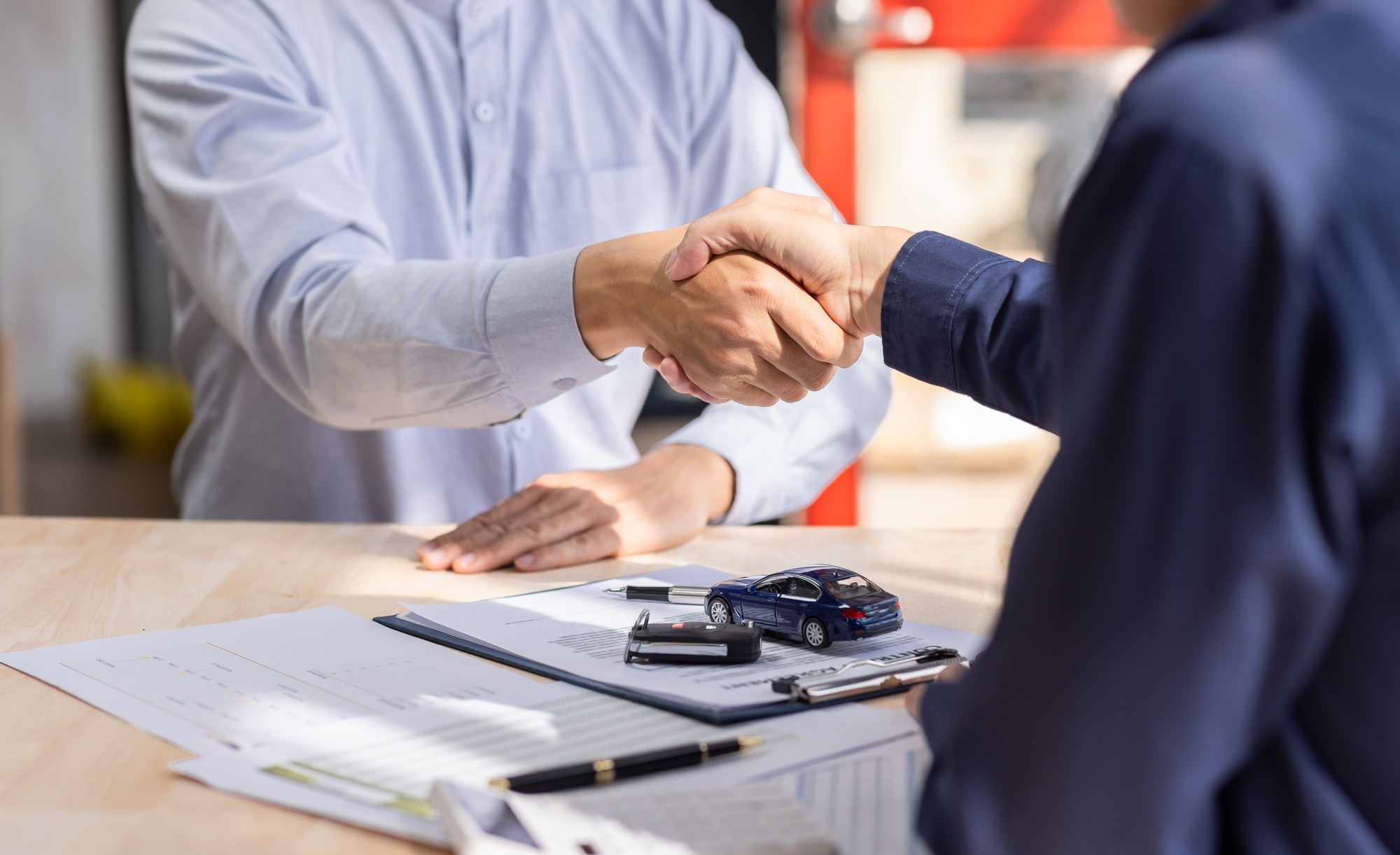 Car rental service sales give the car key concept. Close up view Hand of agent handshake to the